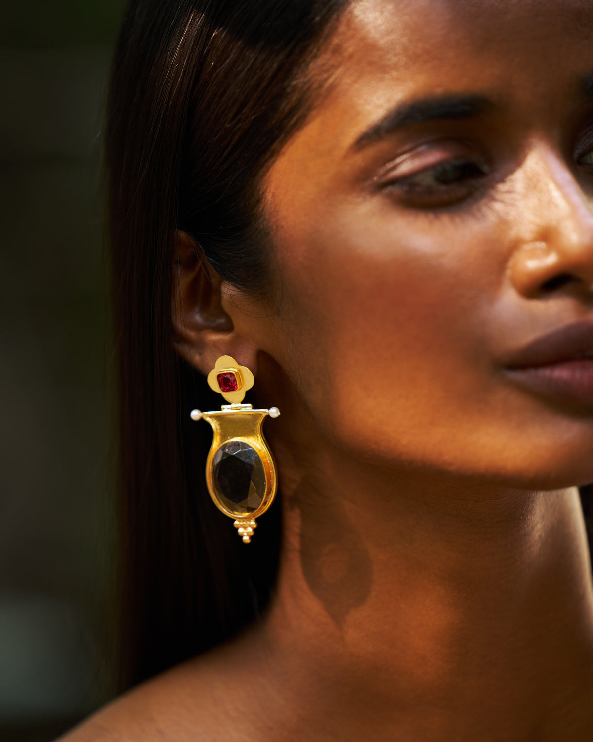 Side profile of a gold eden drop earring with oval glass and pearls.