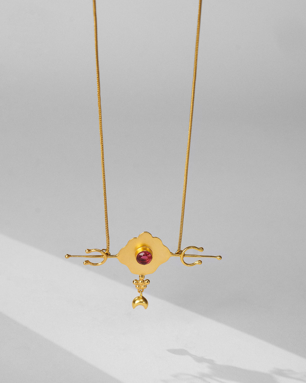 Gold Berber necklace with a pink-red glass pendant and crescent charm.