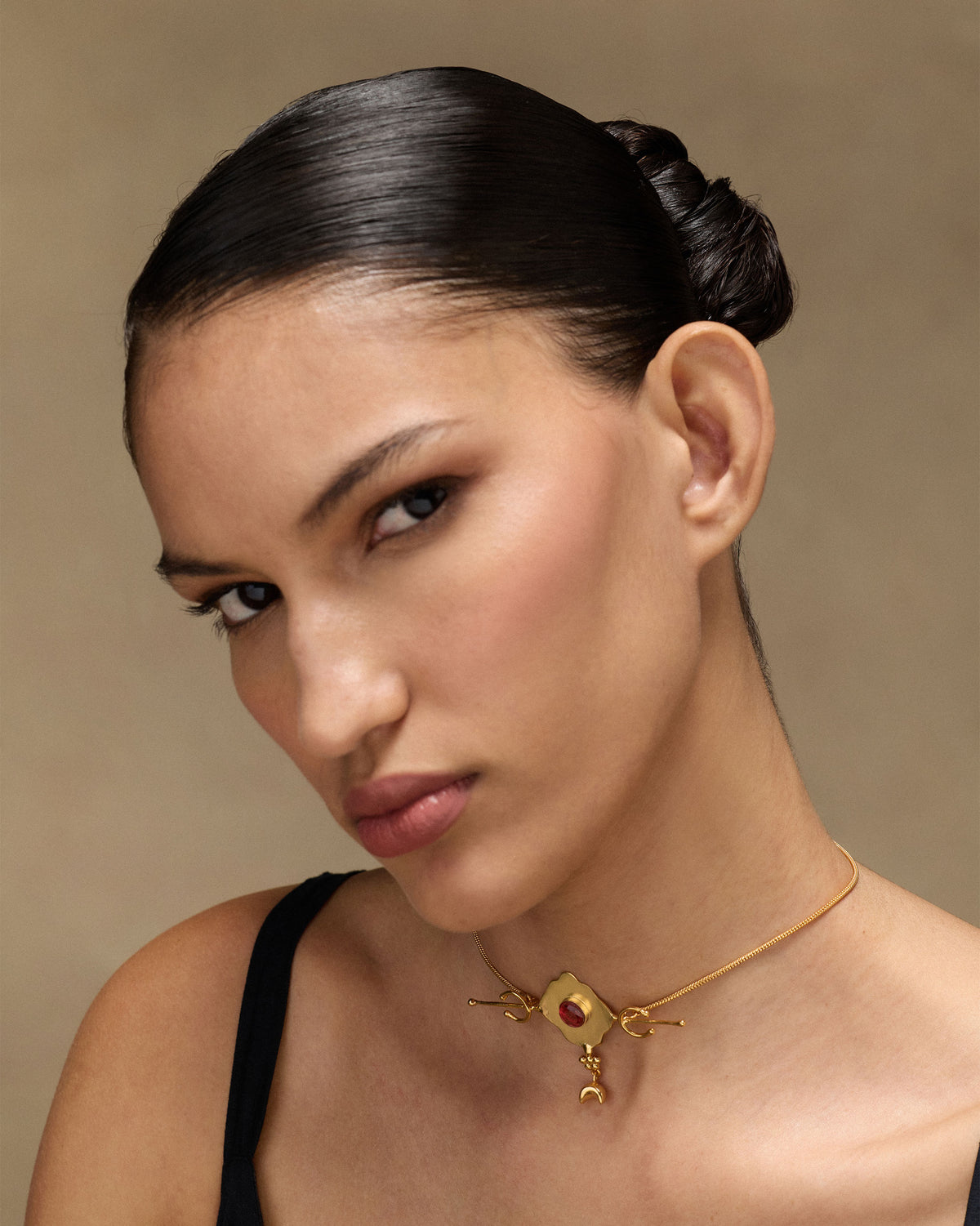 Person wearing a gold Berber necklace with a red glass pendant.