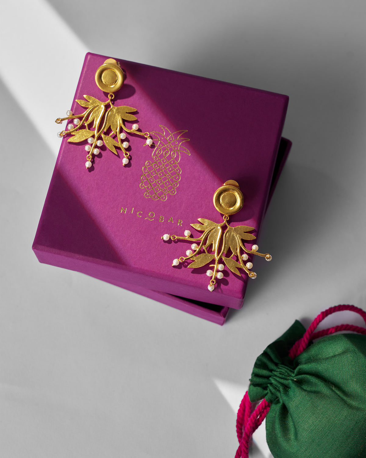 Pair of Anaar Cluster Earrings displayed on a magenta gift box.