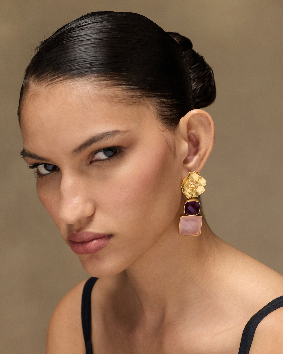 Person wearing gold dessert rose ruby drops with pink stones.
