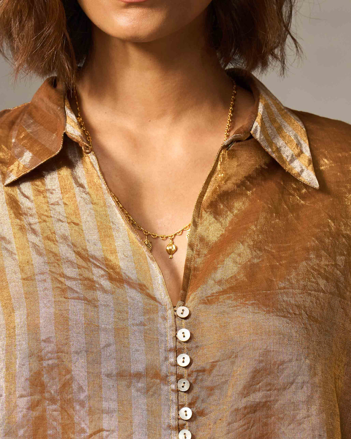 Close-up of the Hala tunic collar and button placket in metallic stripes.