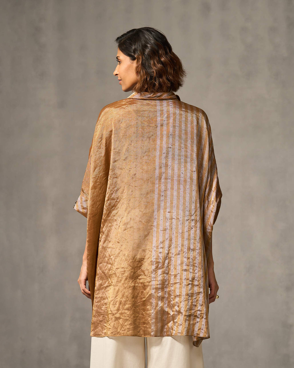 Back of a gold and silver Hala tunic with a striped panel.