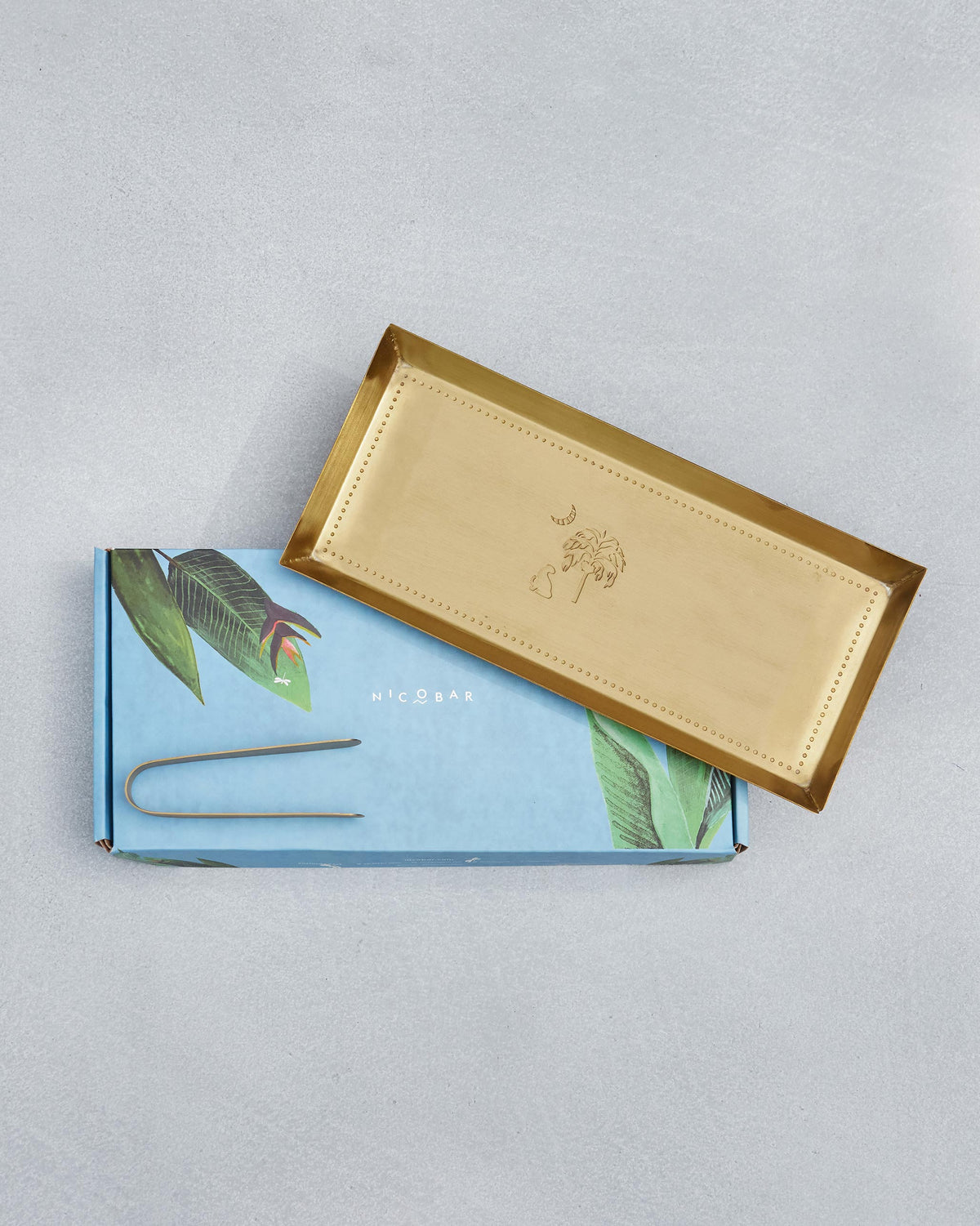 Gold Sahara cookie tray and tongs displayed on a Nicobar gift box.