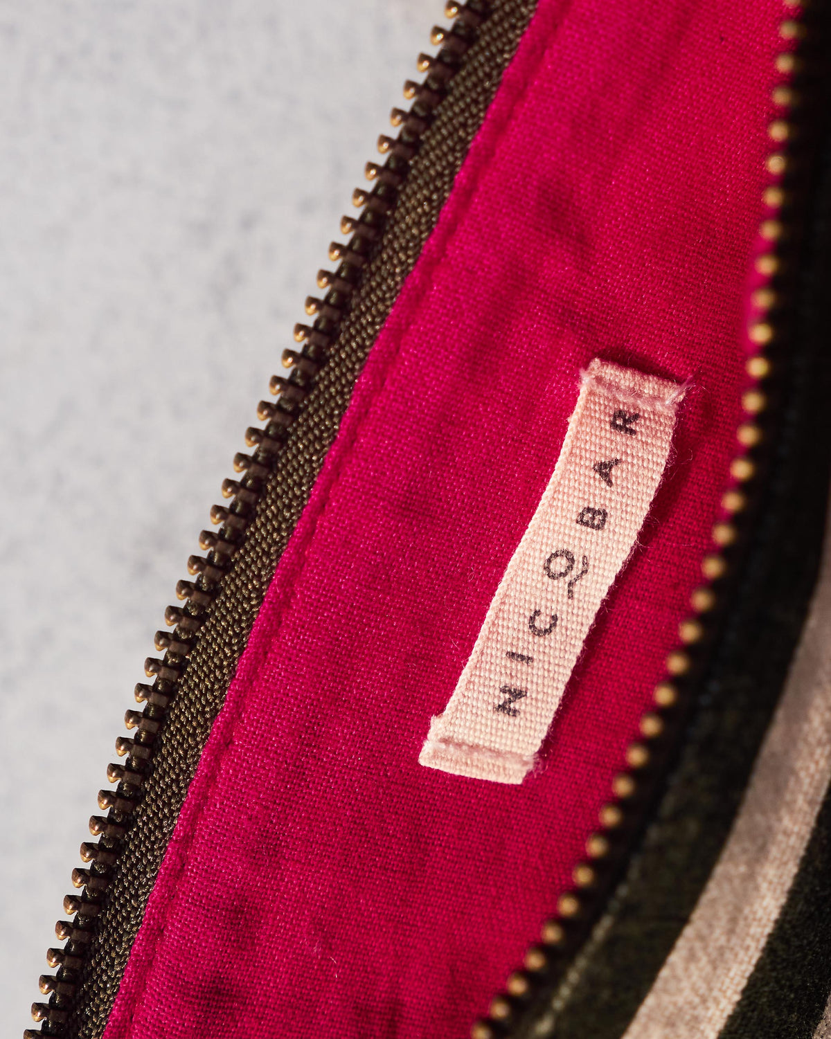 Close-up of the Nicobar woven label inside the Alphabet M Pouch.