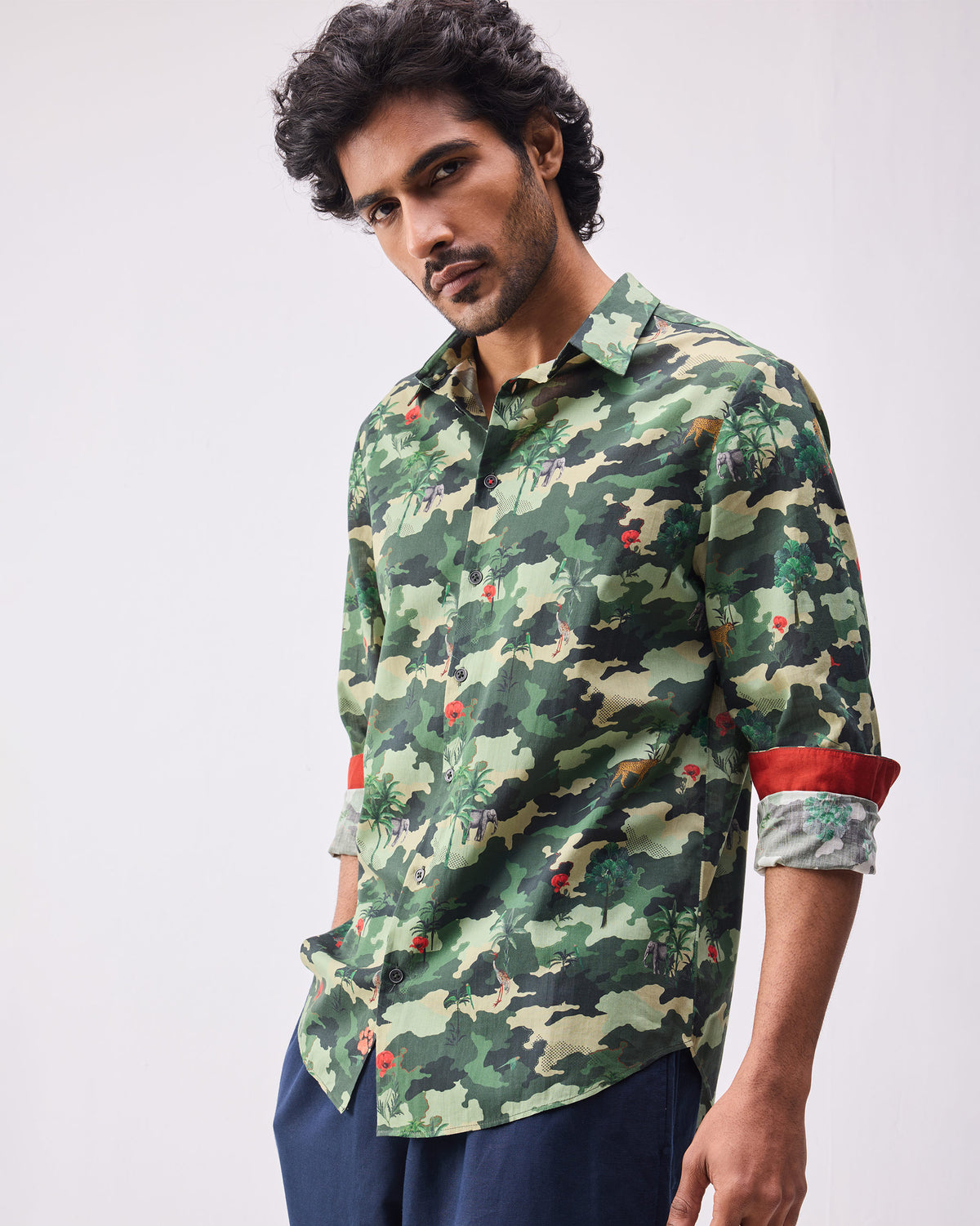 Person wearing a dark green camo Hakuna shirt with red cuff lining.