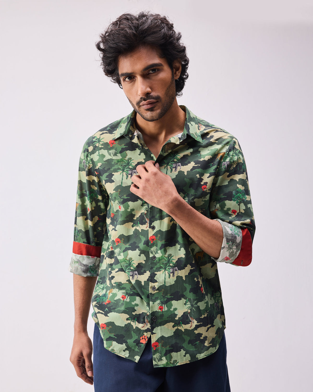 Person wearing a dark green camo Hakuna shirt with animal and palm motifs.