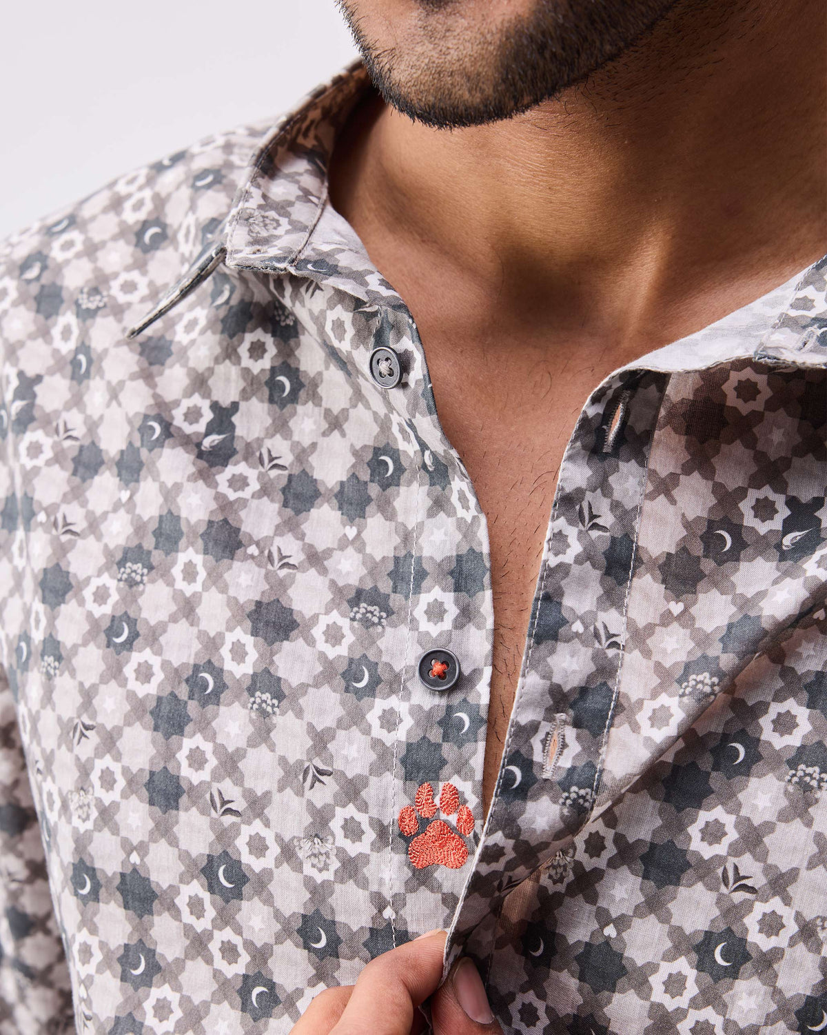 Close-up of a light grey print Kochi shirt showing geometric motifs and an orange placket accent.