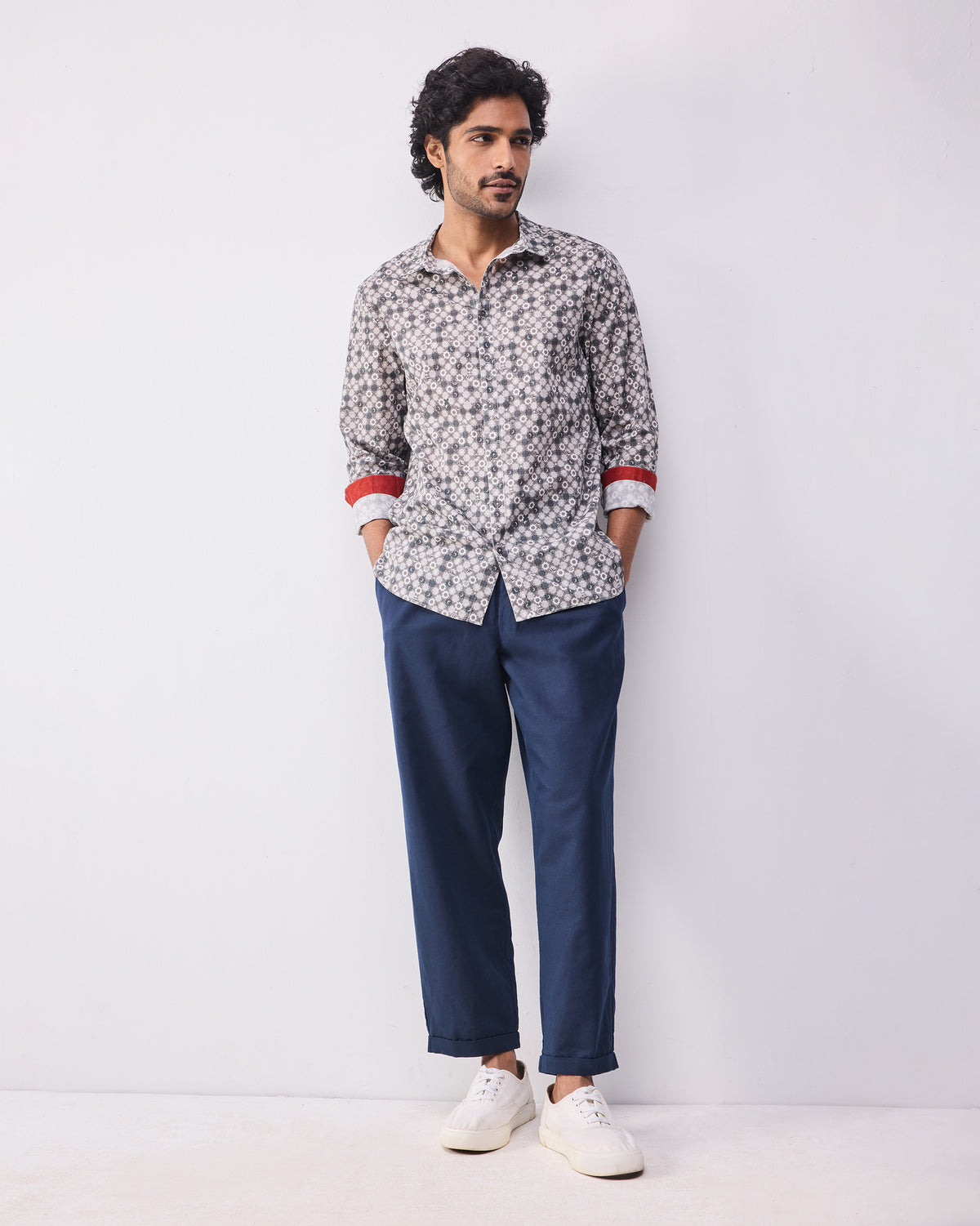 Person wearing a light grey print Kochi shirt untucked over navy trousers.