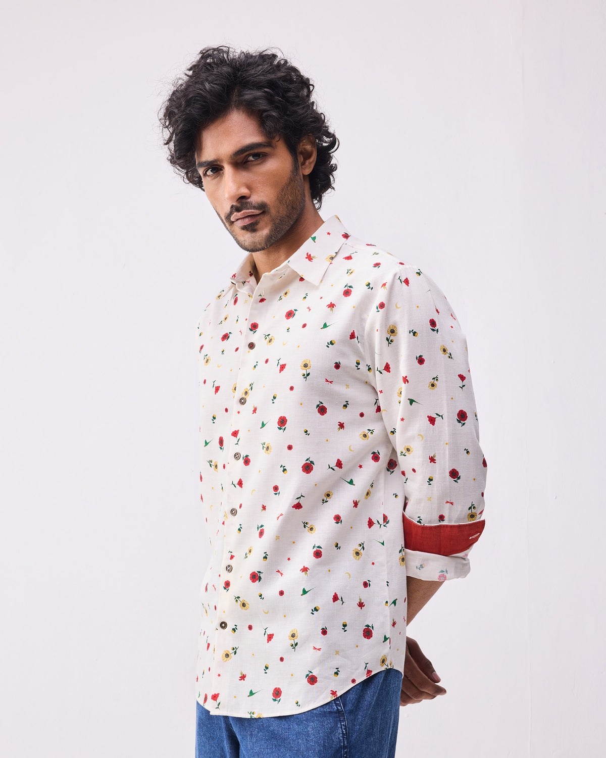 Person wearing an ivory floral Catamaran shirt with a red contrast cuff.