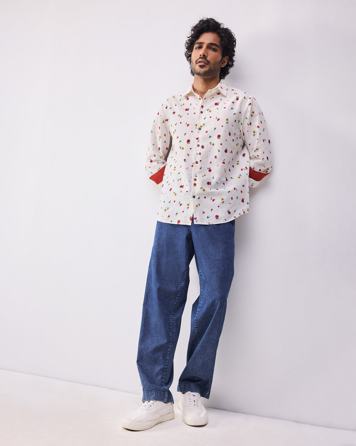 Person wearing an ivory floral Catamaran shirt with red cuff lining.