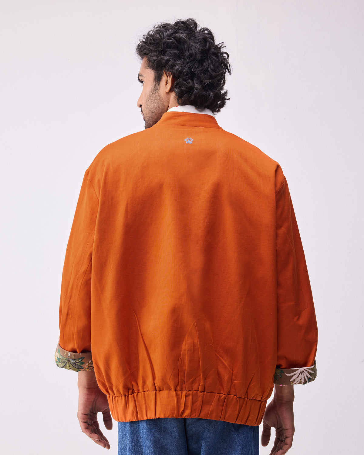 Back of a rust Safar bomber with a paw print and botanical lining.