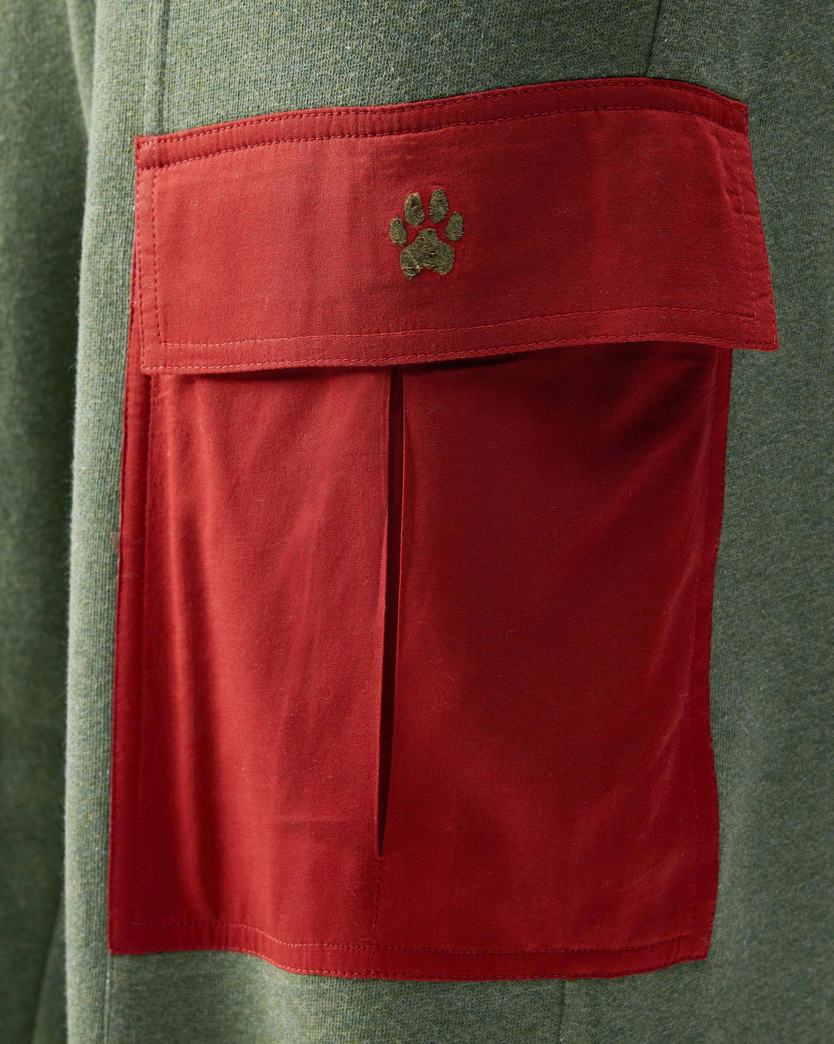 Close-up of green Lounge Pants showing a red flap pocket with a green paw embroidery.