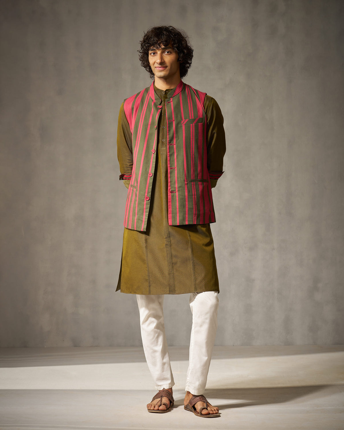 Red and oak brown striped Nehru jacket worn full length over an olive kurta.