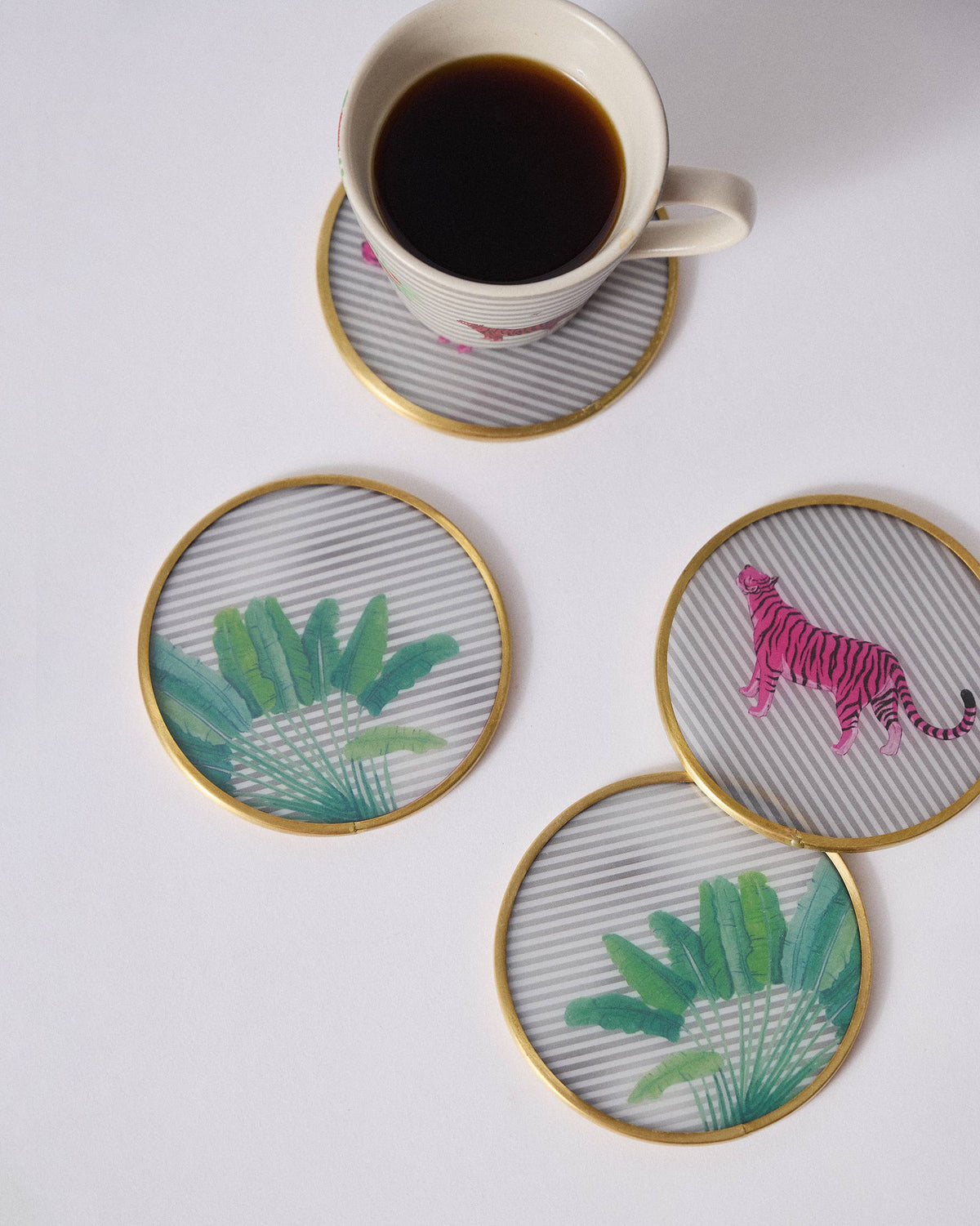 Ceylon Trail coasters in use under a mug, showing pink tiger and leaf motifs.