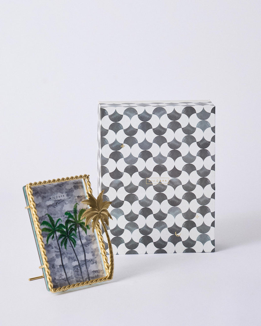 The Gilded Palm frame in front of its grey and white patterned gift box