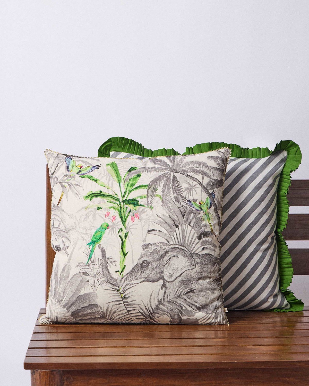 Ceylon Ele cushion cover with jungle elephant and parrot print on a bench.