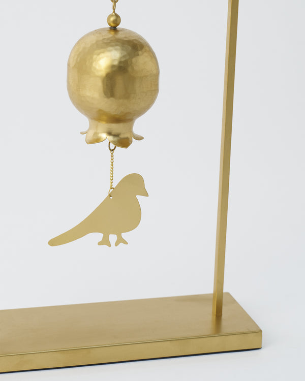 Close view of the hammered gold bell and the bird charm