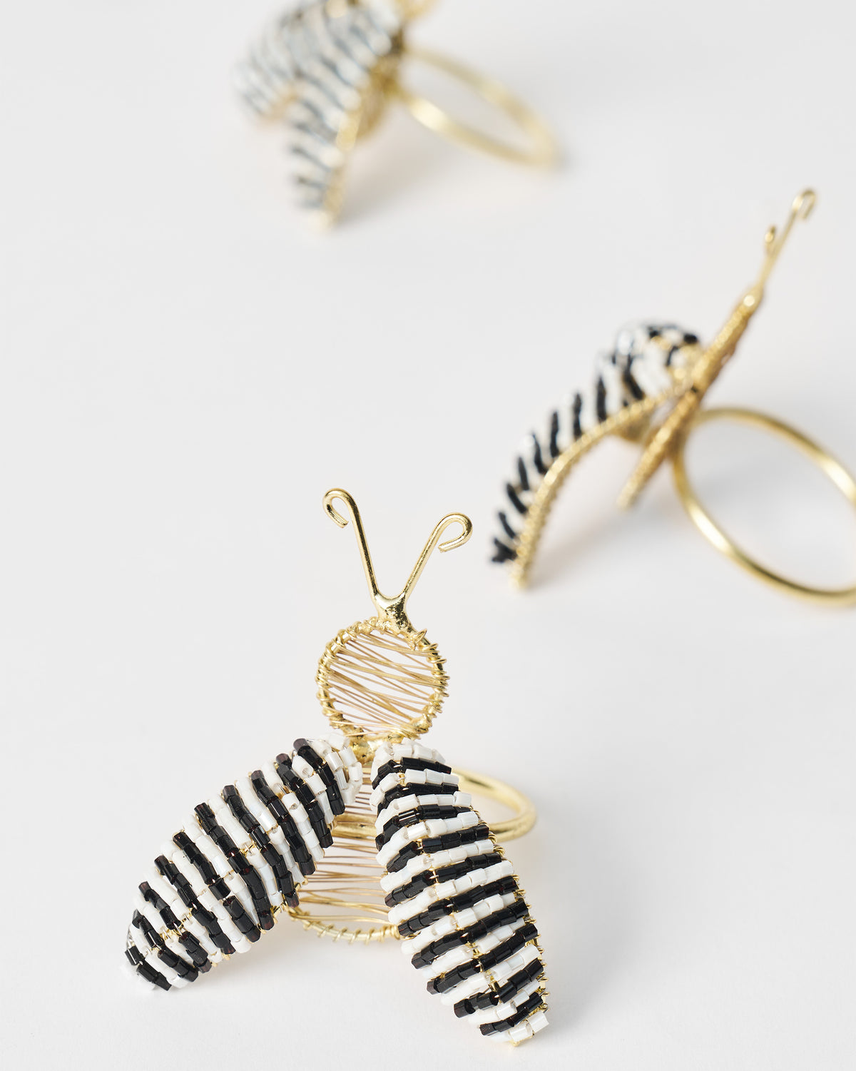 Close-up of a gold-wire bee napkin ring with black and white striped wings.