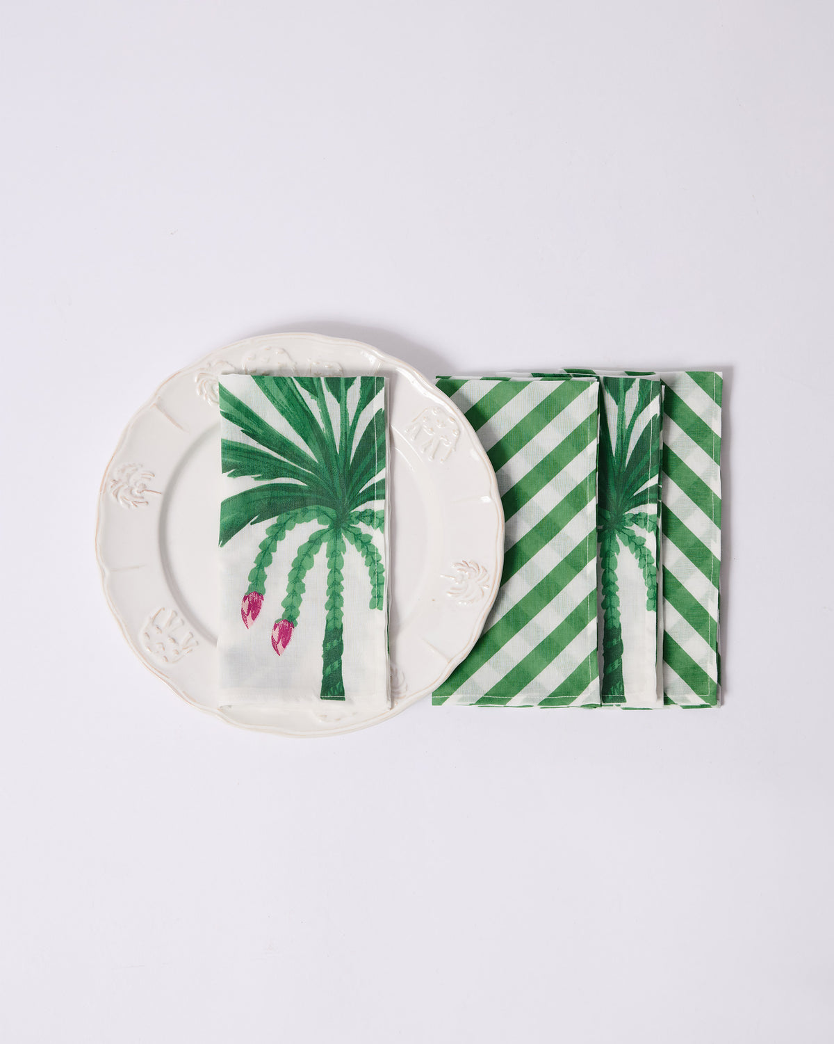 Ceylon Trail palm and stripe napkins stacked beside a cream plate.