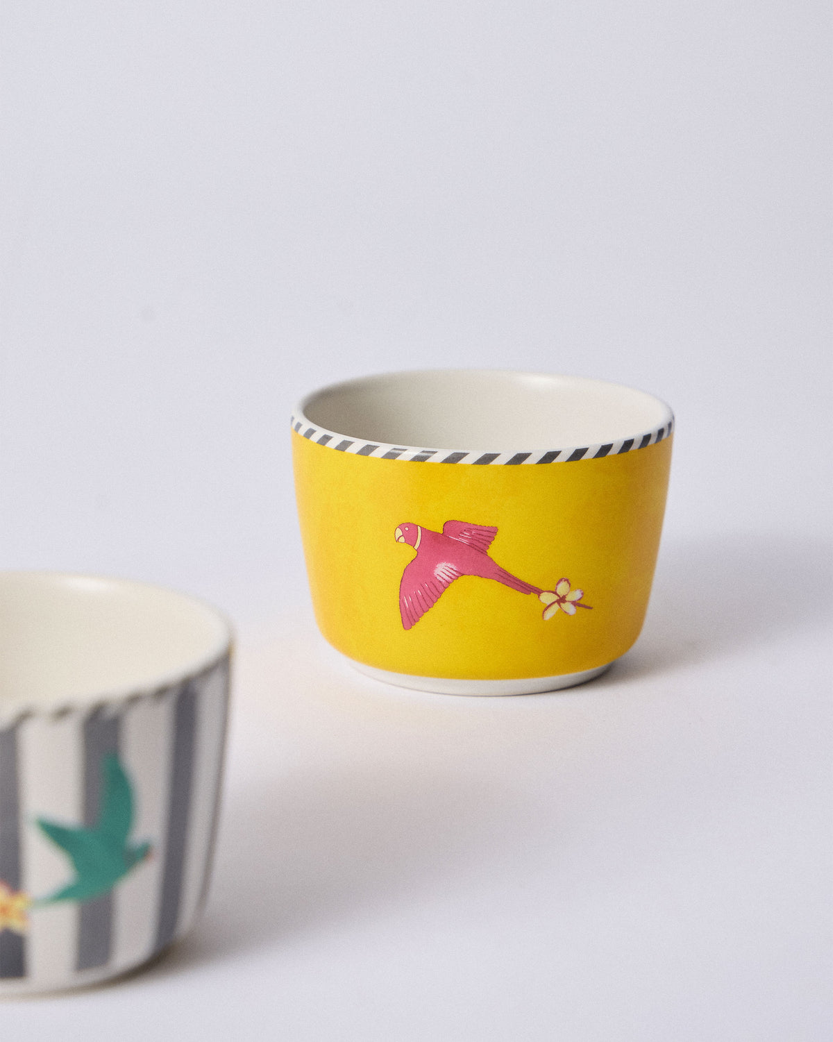 Close-up of a yellow Ceylon Trail Nut Bowl with a pink parrot motif.