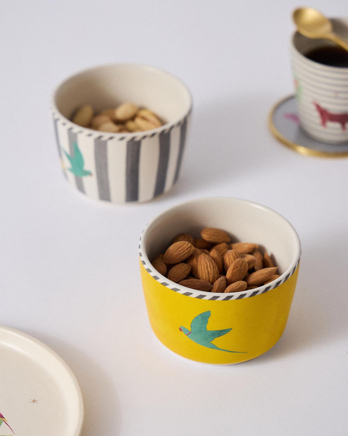 Yellow Ceylon Trail Nut Bowl filled with almonds beside a striped bowl.