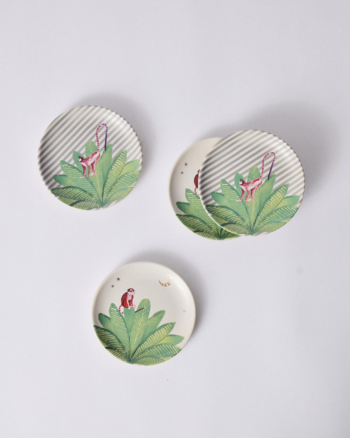 Set of four Ceylon Trail tea plates with pink monkeys on tropical leaves.