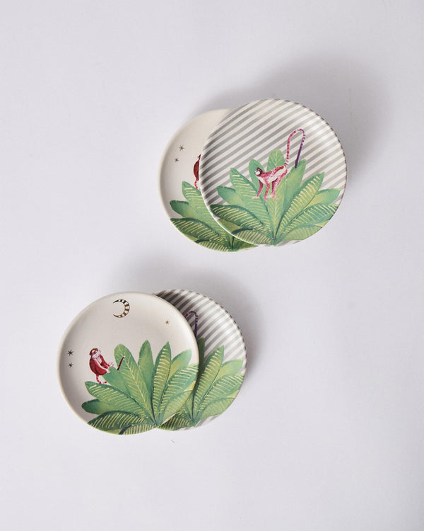Overlapping plates, pink monkeys among leaves and gold moons