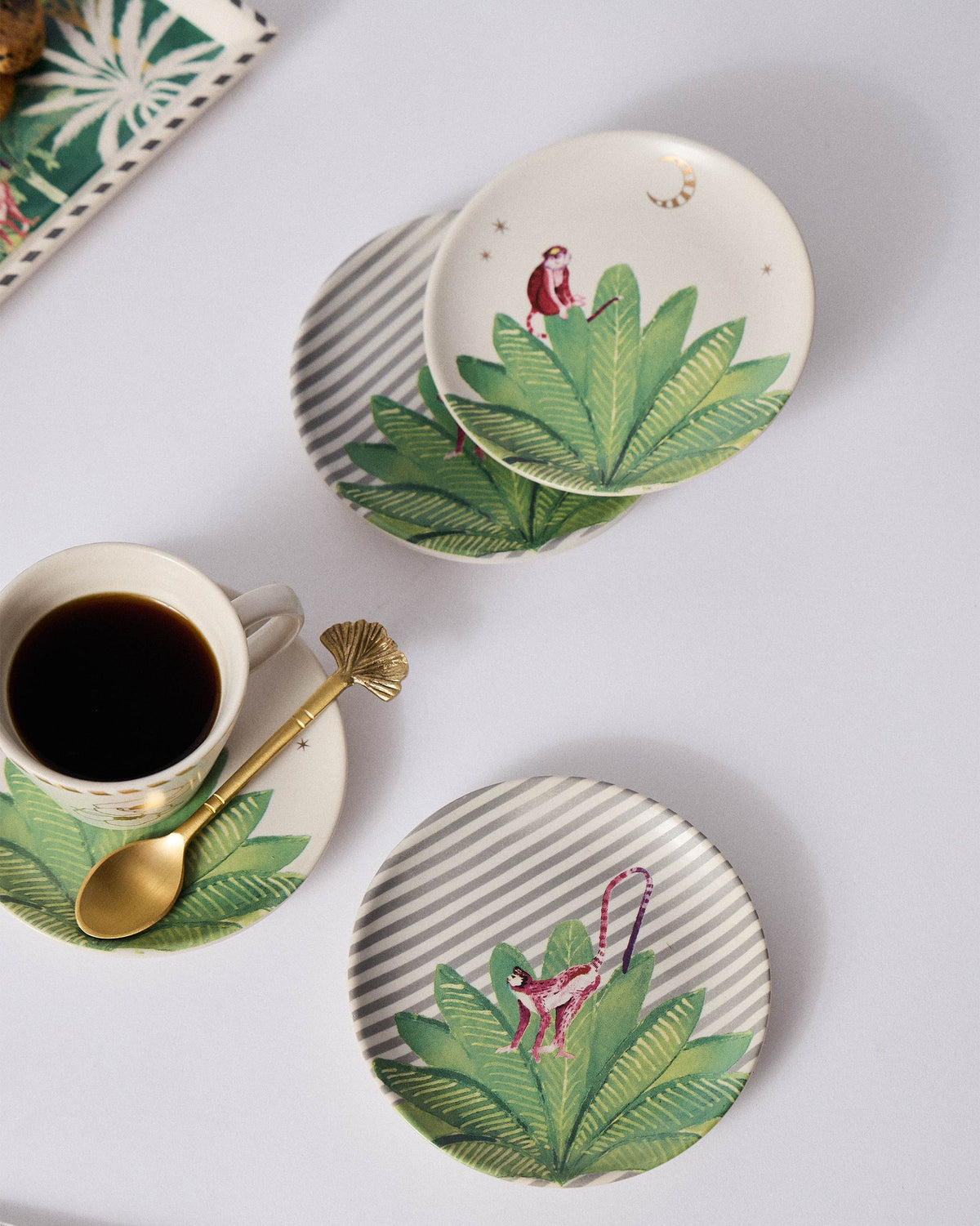 Ceylon Trail tea plates with pink monkeys on leaves, styled with coffee.