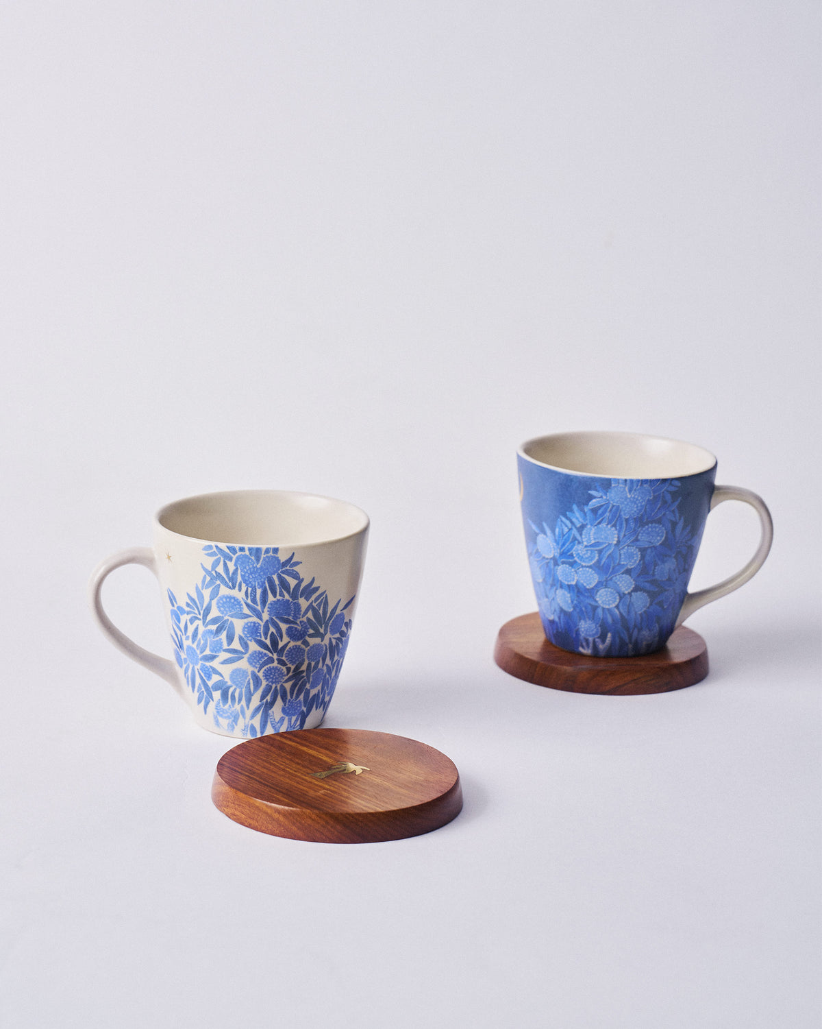 Cream and blue botanical Nadi mugs with a wooden lid and gold bird inlay.
