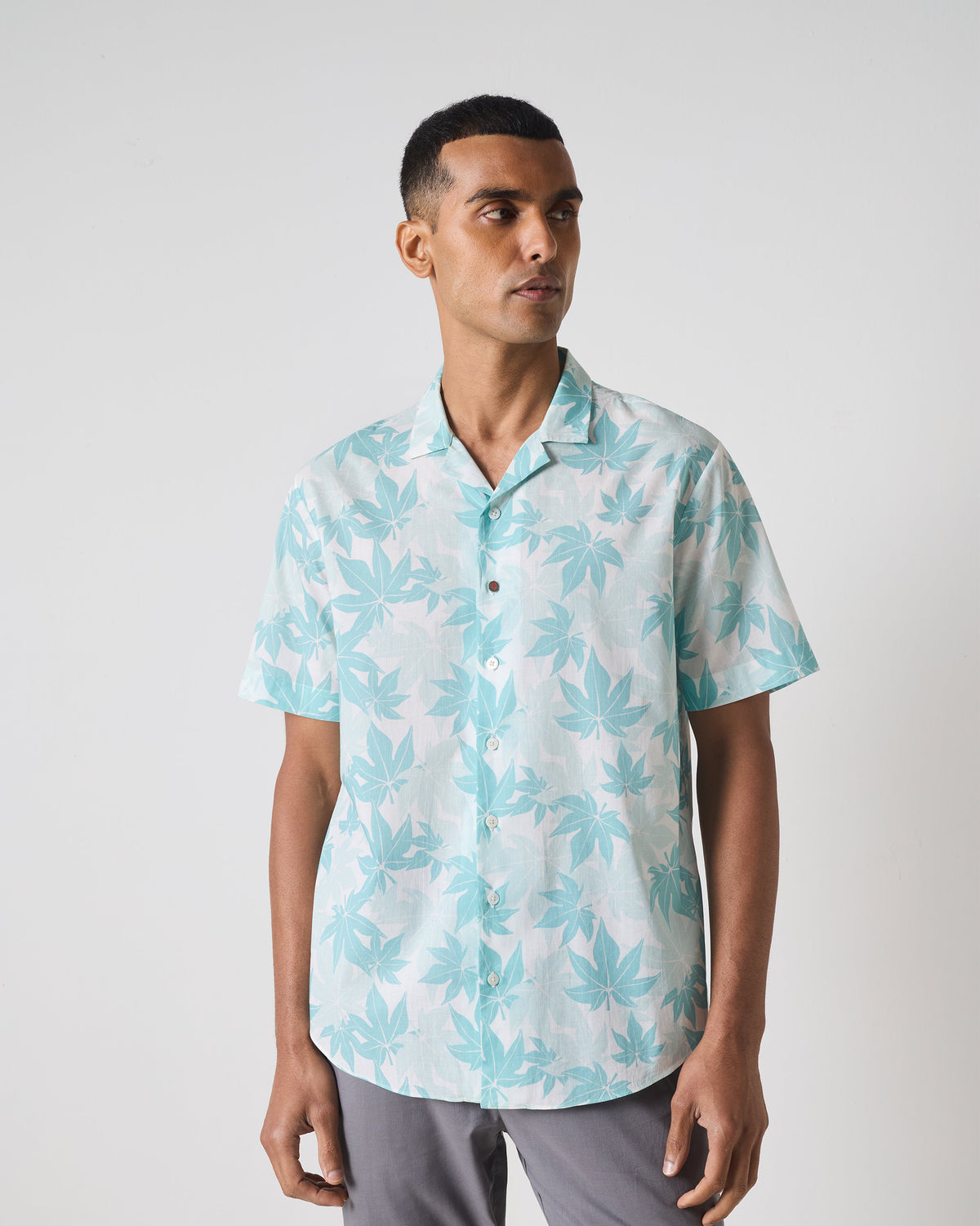 Person wearing a light blue Mistari shirt with a tropical leaf print.