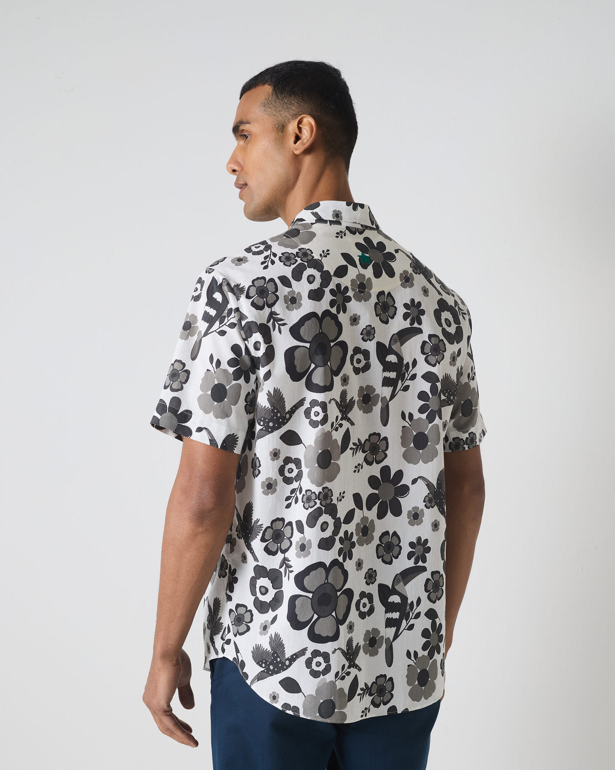 Back of a black and white Mistari shirt with a floral bird print and green embroidery.