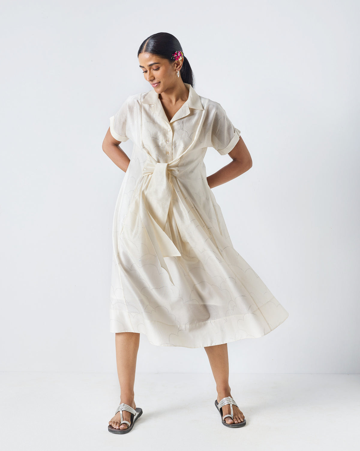 Person wearing an ivory Cadeau Dress with a silver print and waist tie.