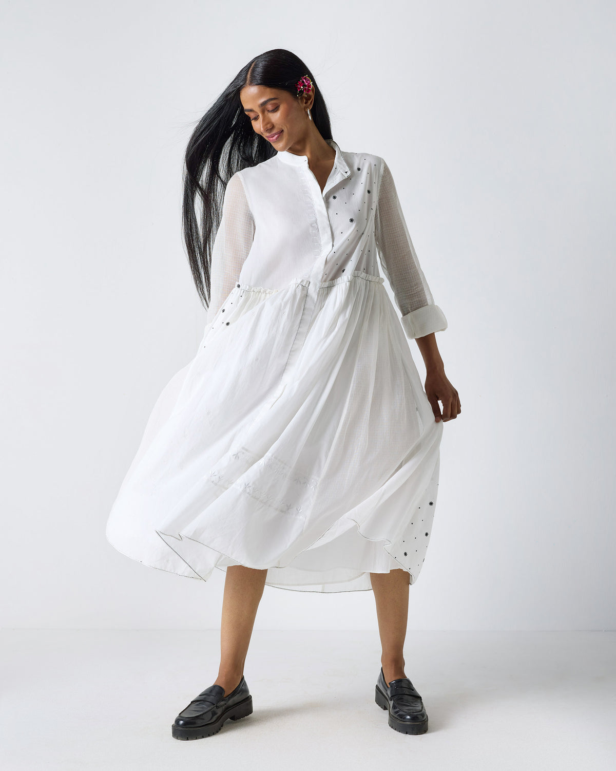 Person wearing a white Rayna dress with a flared skirt and black embroidery accents.