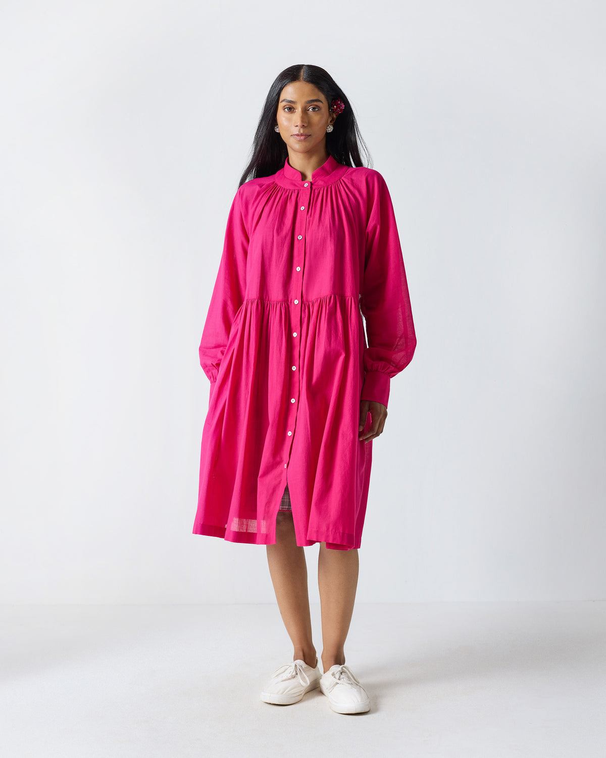 Person wearing a fuchsia Miya dress with a full button placket and tiered skirt.