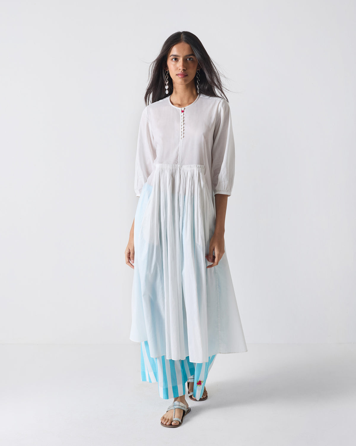 Person wearing a white Pleated Waist kurta with an empire waist and flared hem.