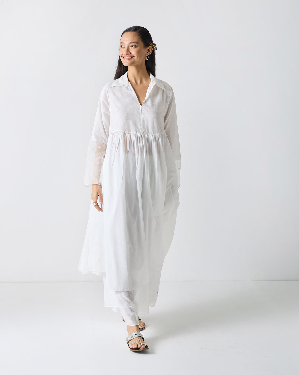 Person wearing a long white embroidered kurta.