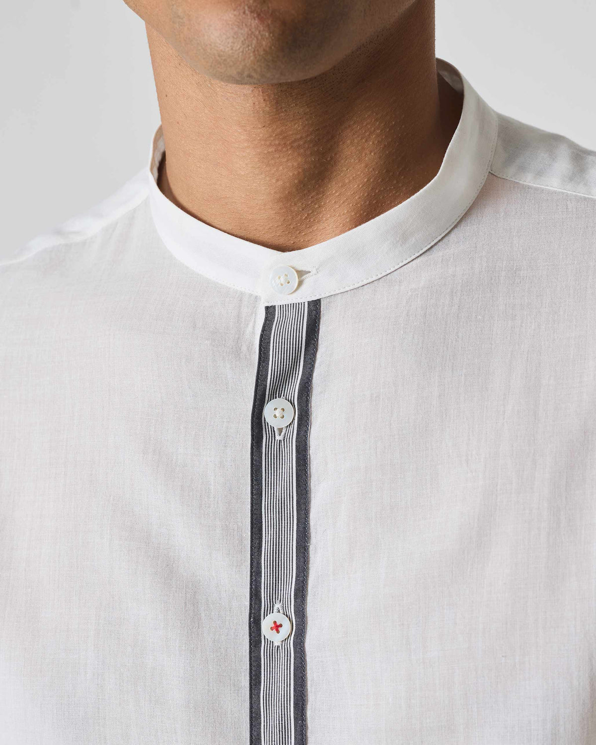 Close-up of a white Neil shirt collar with striped placket trim.