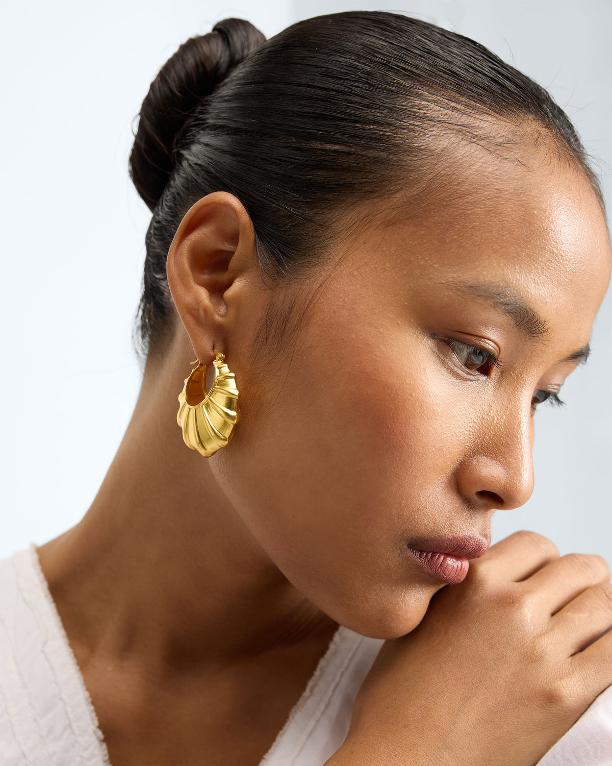 Person wearing gold Shell Balis, face turned to the side.