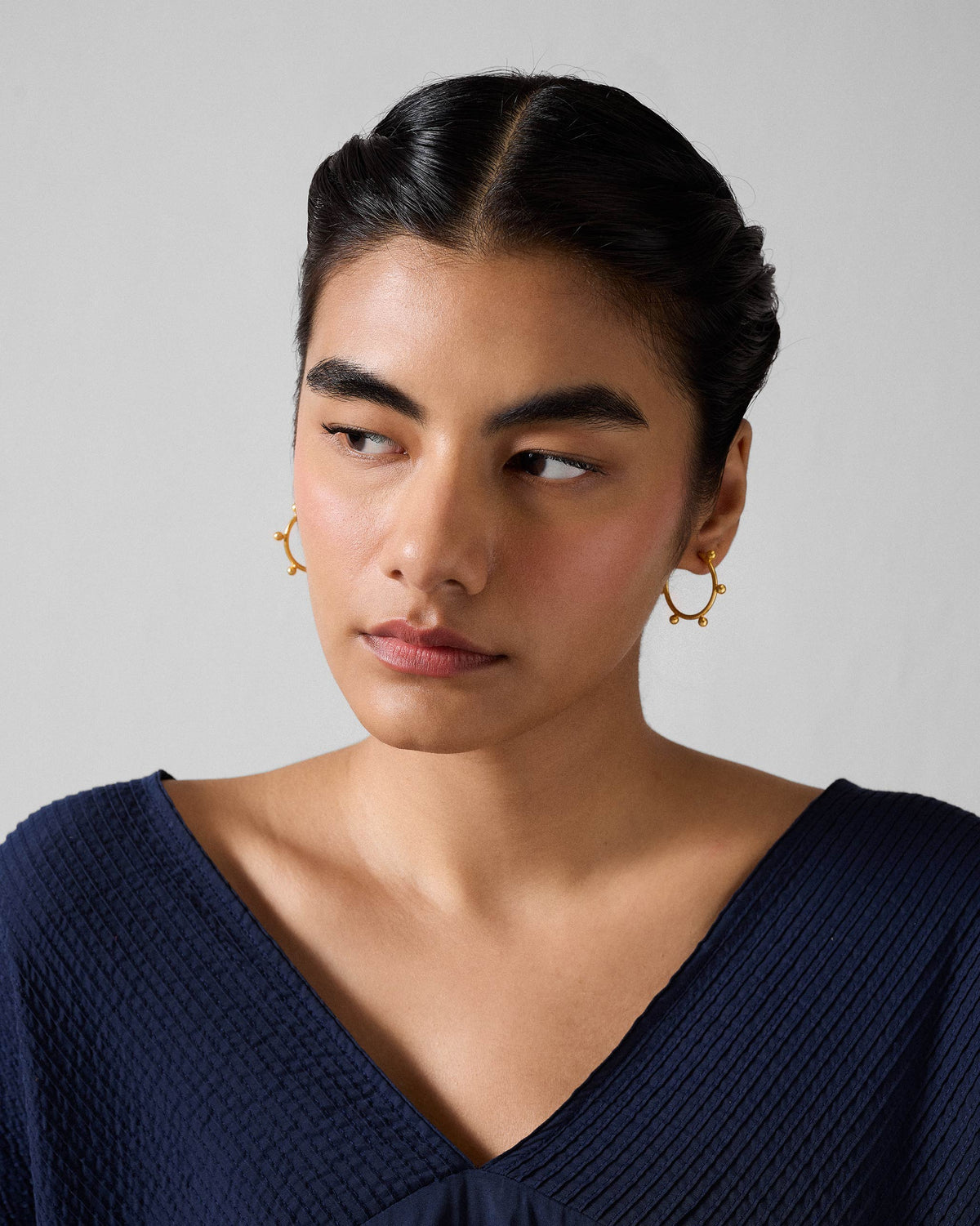 Person wearing gold Sunshine hoops with bead accents.
