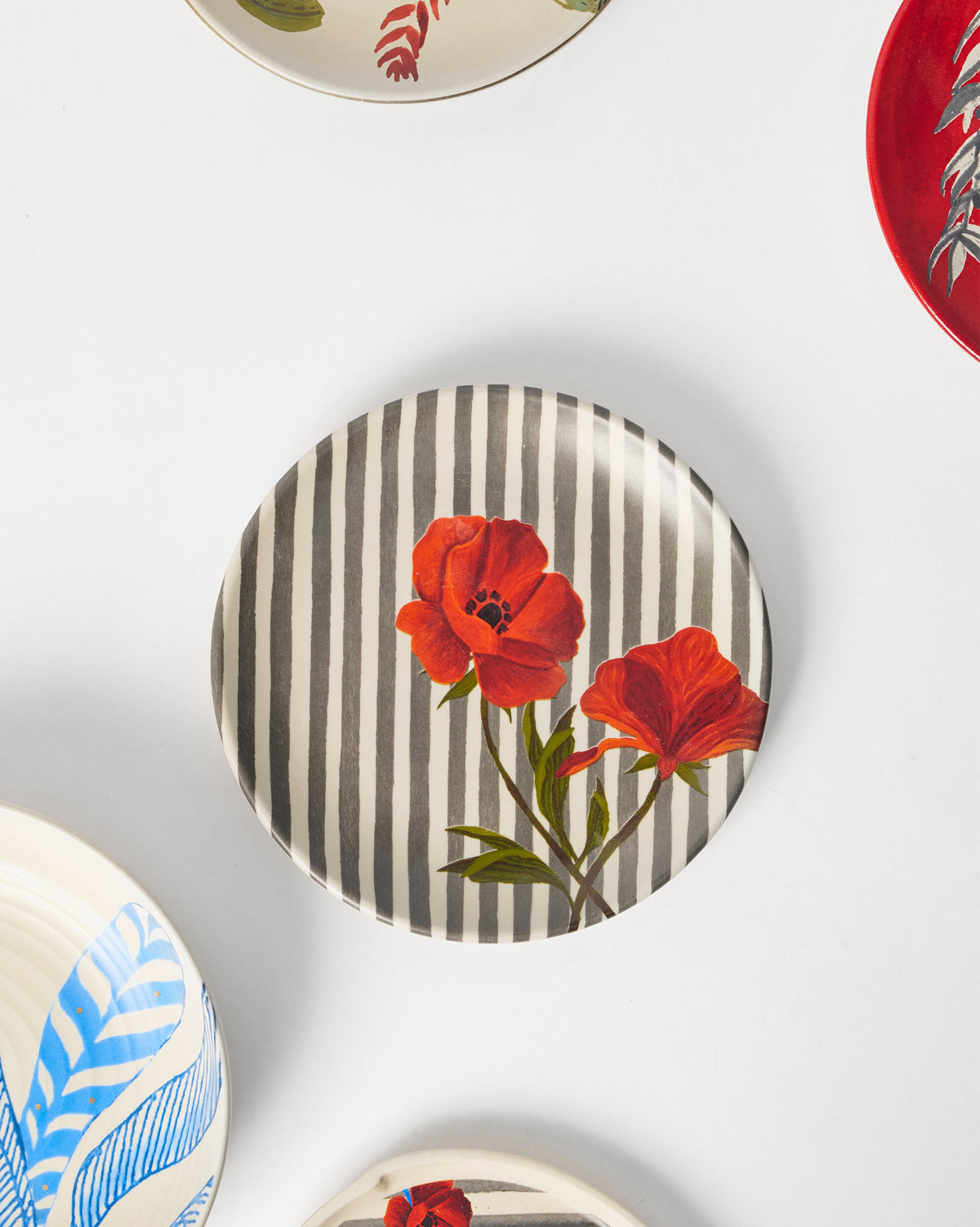 Striped Poppy quarter plate styled among coordinating ceramic plates.
