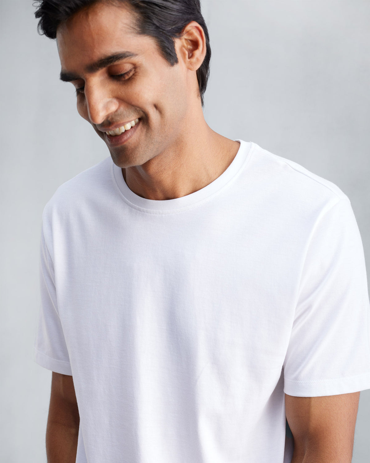Close-up of a person wearing a white Everyday Essentials t-shirt.