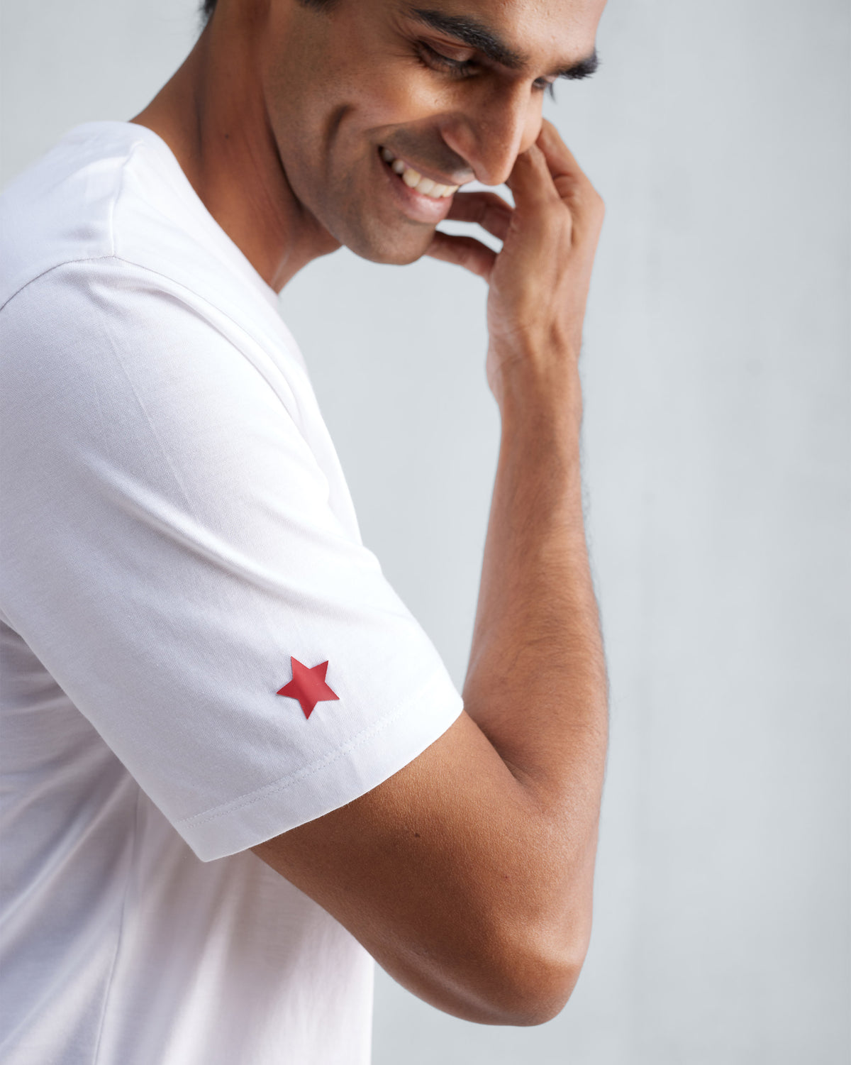 Close-up of a white Everyday T-shirt sleeve showing a red star detail.