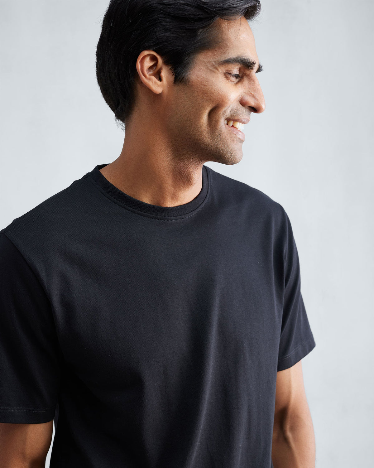 Close-up of a person wearing a black Everyday Essentials t-shirt.