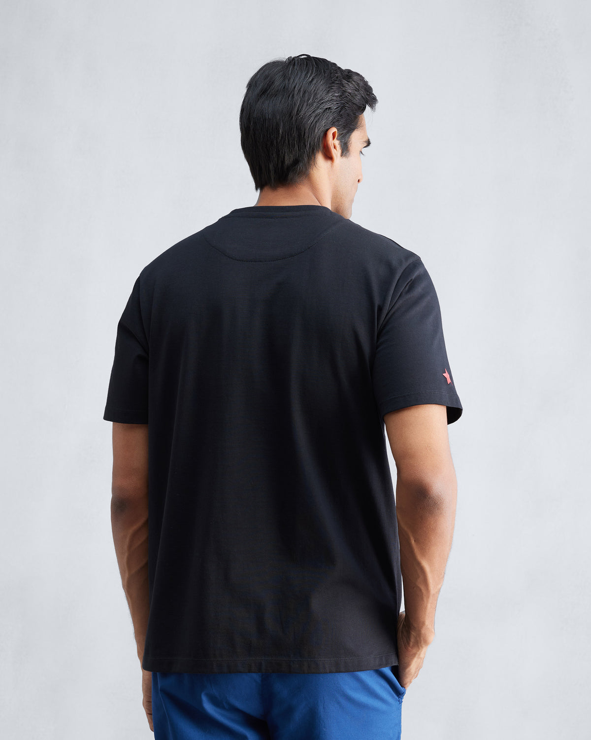 Back of a black Everyday T-shirt with a clean hem and red star on the sleeve.
