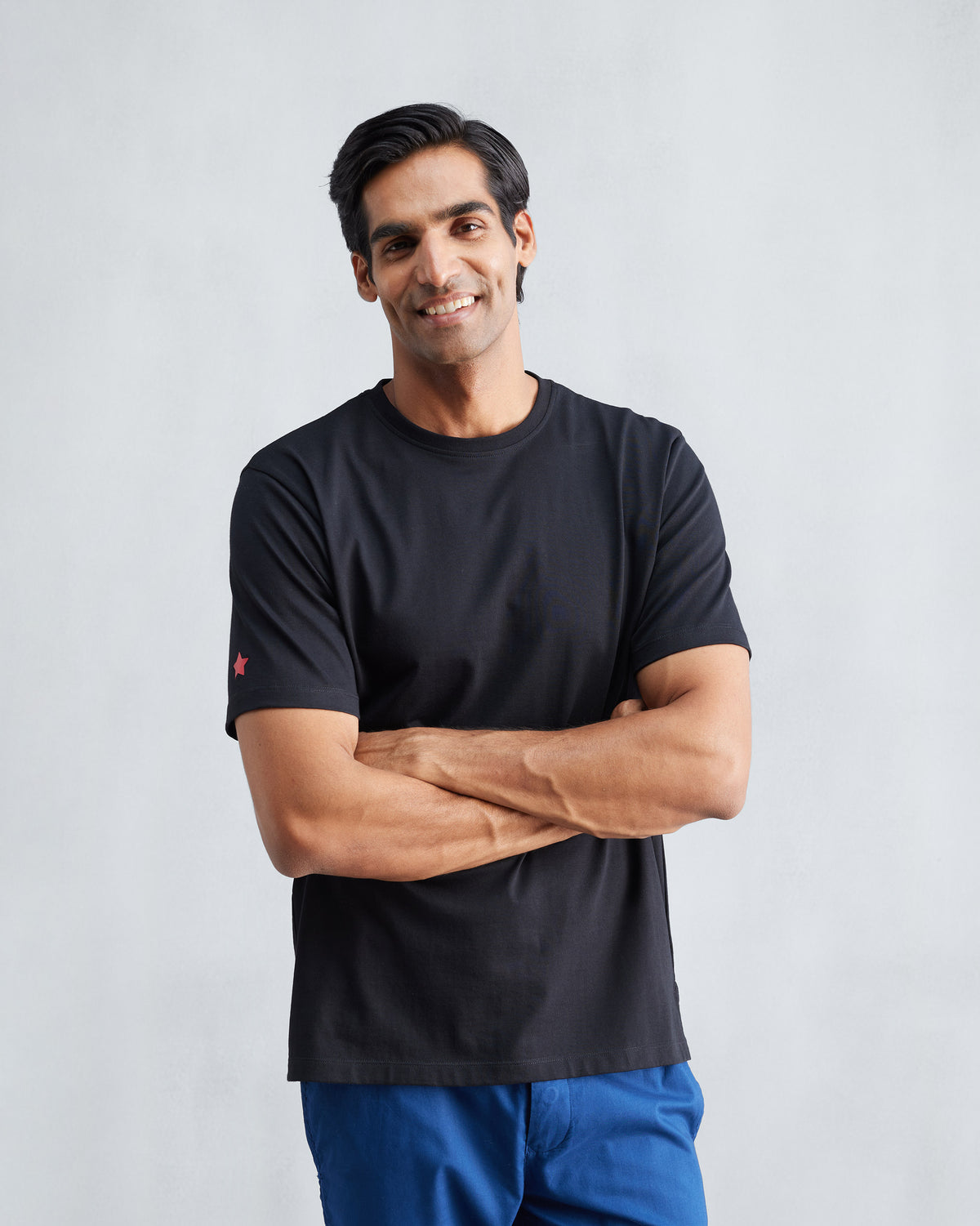 Person wearing a black Everyday T-shirt with a red star on the sleeve.