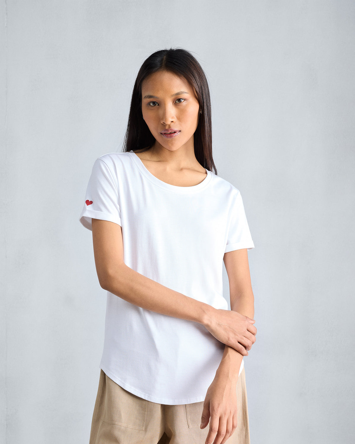 Person wearing a white crew-neck Basic T-Shirt with a red sleeve heart.
