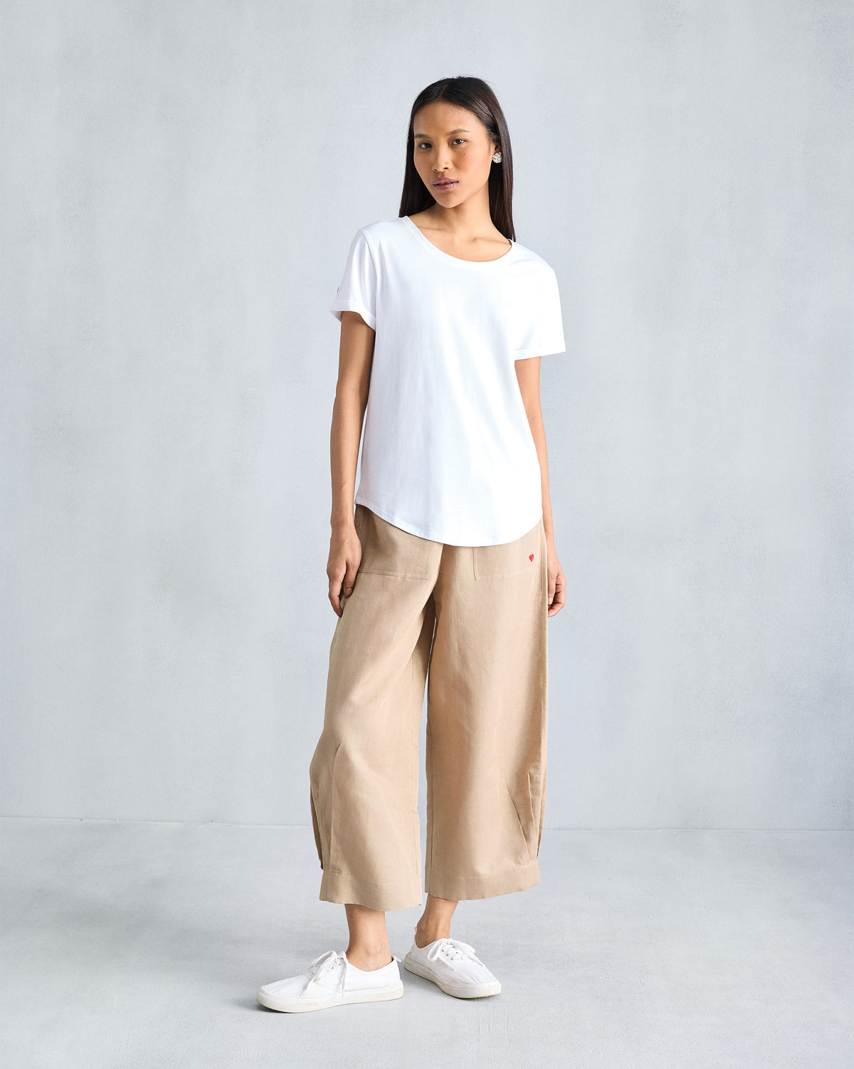 Person wearing a white Basic T-Shirt with a curved hem.