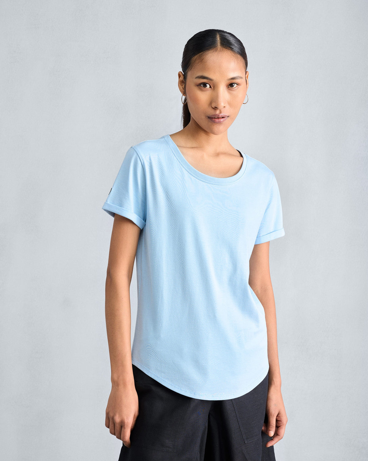 Person wearing a light blue Basic t-shirt with a curved hem.