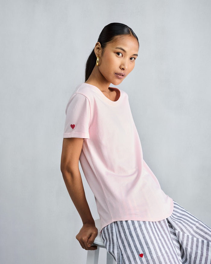 Person wearing the Basic T-Shirt in blush pink with a heart on the sleeve.